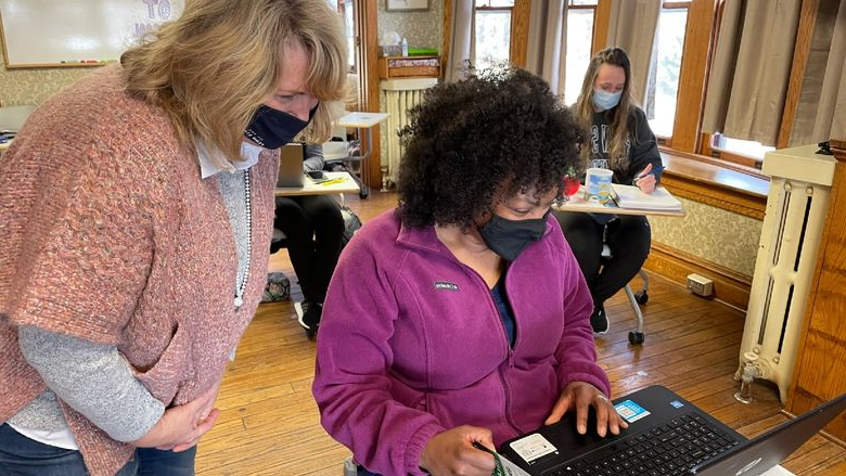 女学生在老师的帮助下学习计算机 